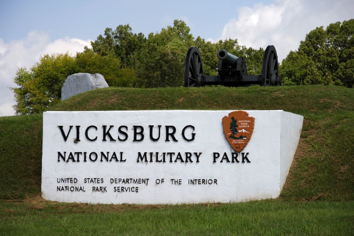A cannon sits above a sign for Vicksburg National Military Park